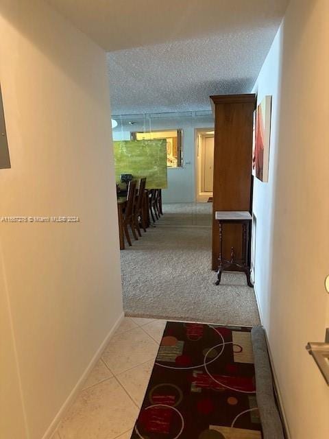 hallway featuring a textured ceiling and light tile patterned floors