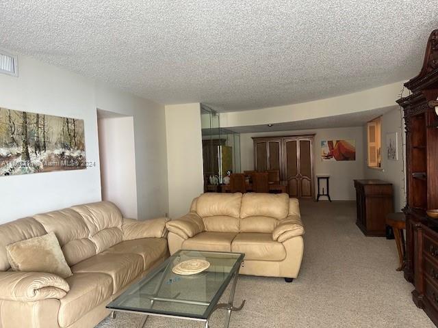 living room featuring a textured ceiling and light colored carpet