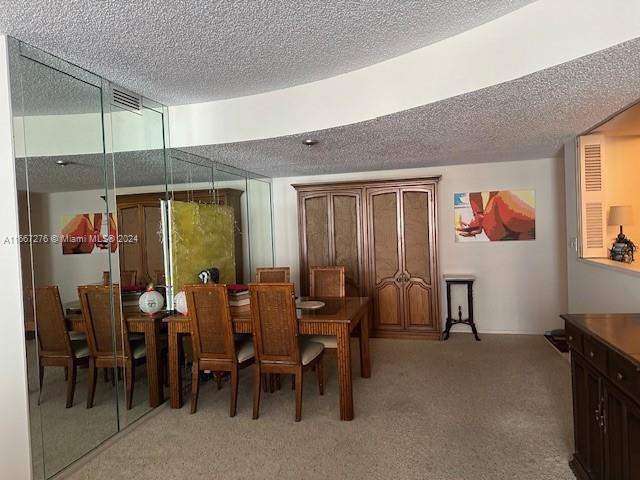 dining space featuring a textured ceiling and light carpet