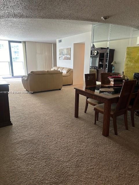 carpeted dining space with a textured ceiling