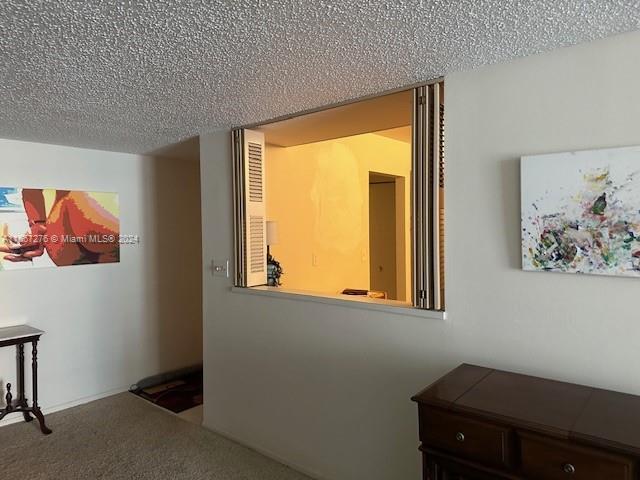 hallway with carpet floors and a textured ceiling