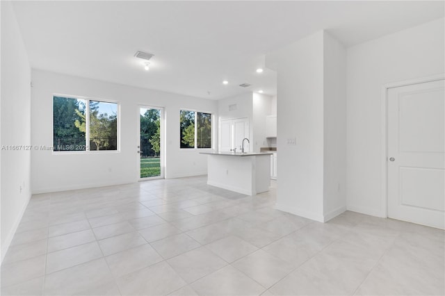 unfurnished living room featuring light tile patterned floors and sink