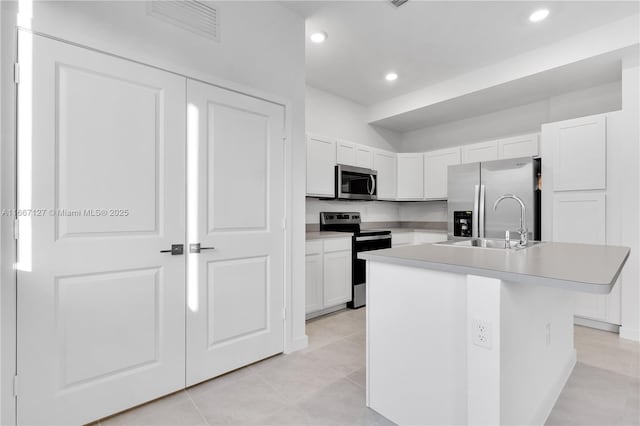 kitchen featuring sink, stainless steel appliances, light tile patterned floors, a center island with sink, and white cabinets