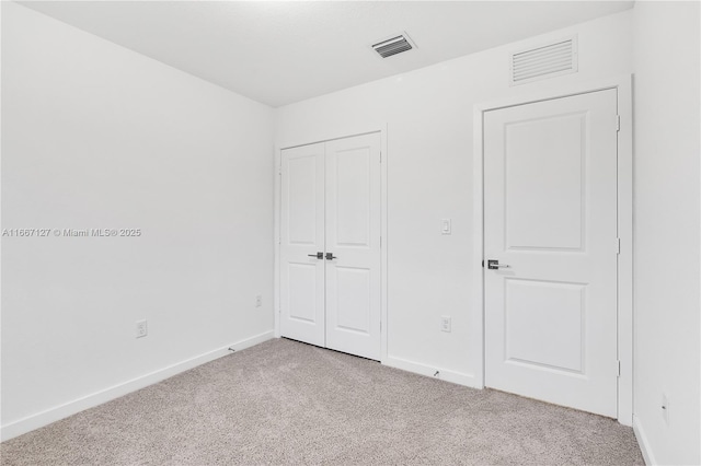 unfurnished bedroom featuring a closet and light colored carpet