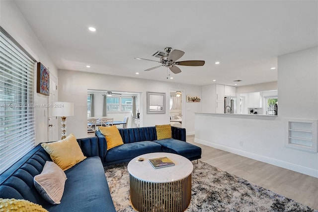 living room with light hardwood / wood-style flooring, a wealth of natural light, and ceiling fan