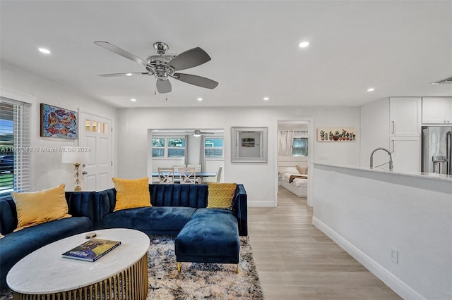 living room with ceiling fan and light hardwood / wood-style flooring