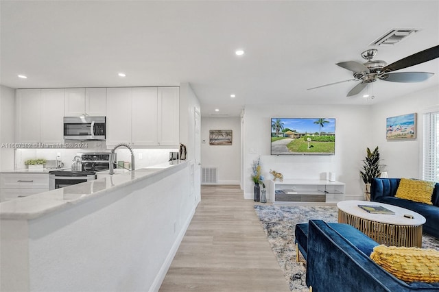 kitchen featuring white cabinets, ceiling fan, light stone countertops, light wood-type flooring, and stainless steel appliances