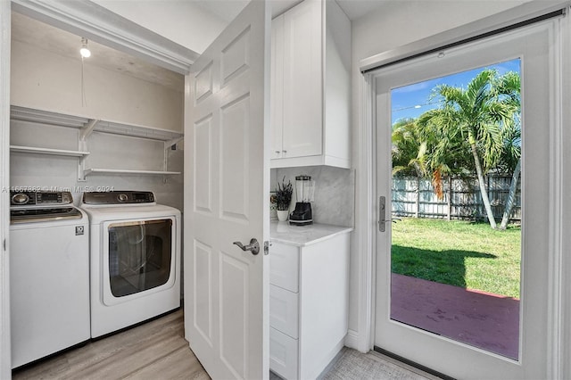 clothes washing area with independent washer and dryer and light hardwood / wood-style flooring