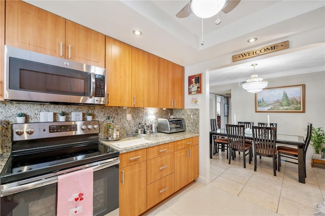 kitchen with light stone counters, backsplash, appliances with stainless steel finishes, light tile patterned floors, and ornamental molding