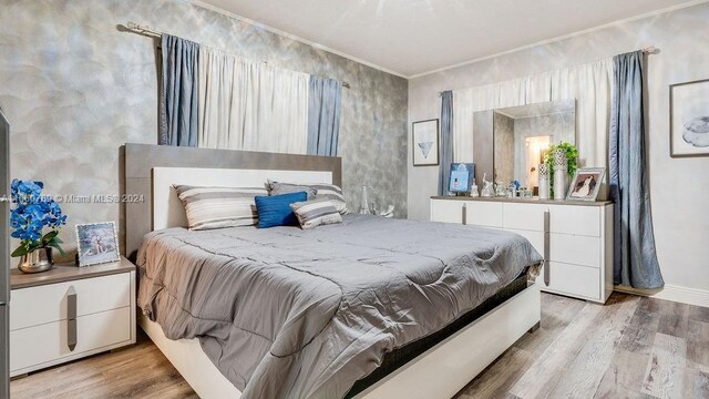 bedroom featuring light wood-type flooring, baseboards, and ornamental molding