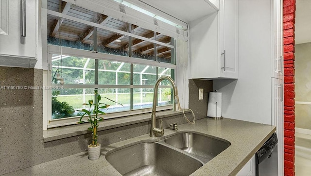 kitchen with stainless steel dishwasher, a sink, white cabinetry, and plenty of natural light