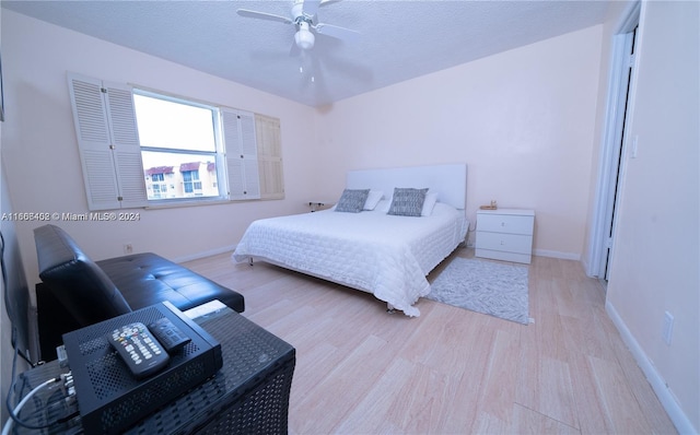 bedroom with light hardwood / wood-style floors, ceiling fan, and a textured ceiling