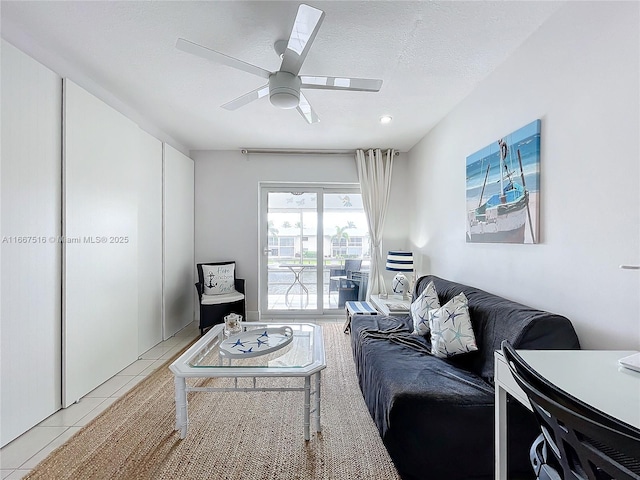 living room with ceiling fan, light tile patterned flooring, and a textured ceiling