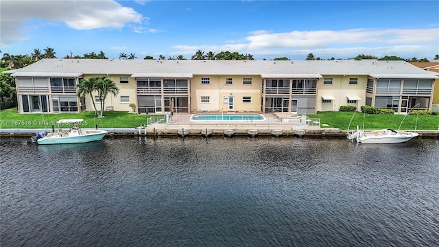 back of property with a lawn and a water view