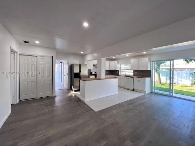 kitchen featuring white cabinets, stainless steel fridge, tasteful backsplash, light hardwood / wood-style flooring, and dishwasher