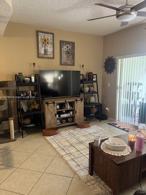 living room with a textured ceiling, tile patterned floors, and ceiling fan