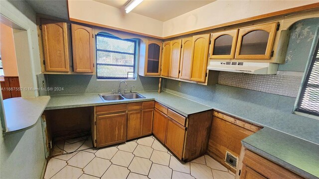 3230 N 23rd Ave, Hollywood, FL 33020 - kitchen featuring glass insert cabinets, tasteful backsplash, under cabinet range hood, a sink, and brown cabinets