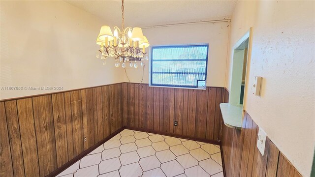 3230 N 23rd Ave, Hollywood, FL 33020 - unfurnished dining area with wooden walls, a wainscoted wall, a notable chandelier, and light floors
