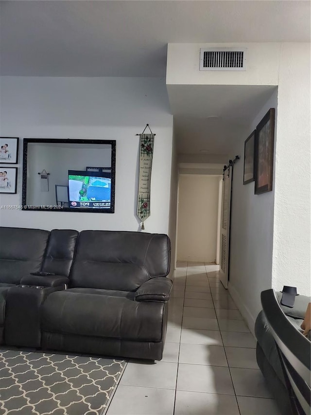 living room with a barn door and tile patterned floors