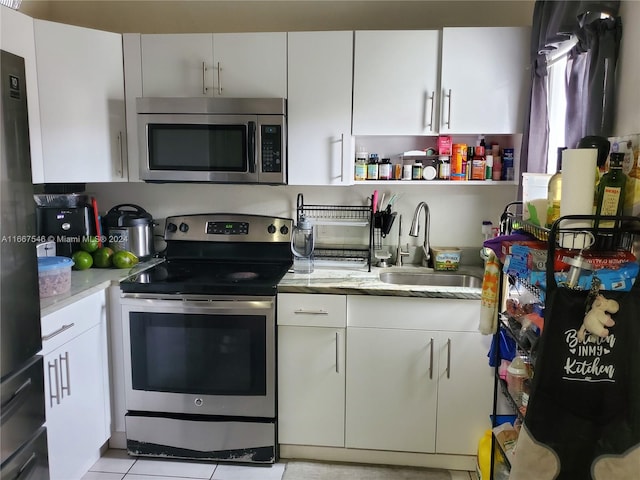 kitchen featuring white cabinets, light tile patterned flooring, stainless steel appliances, and sink