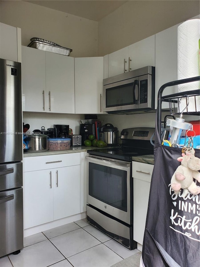 kitchen featuring white cabinets, appliances with stainless steel finishes, and light tile patterned floors