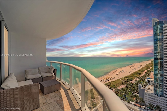 balcony at dusk with an outdoor hangout area, a view of the beach, and a water view