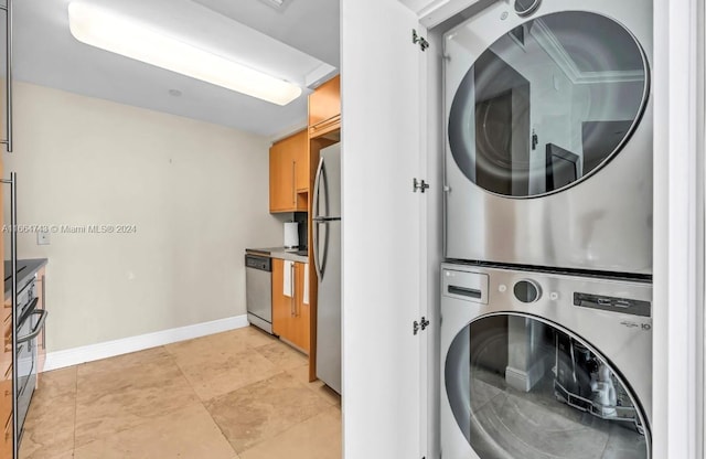 washroom with baseboards, stacked washer / dryer, and laundry area