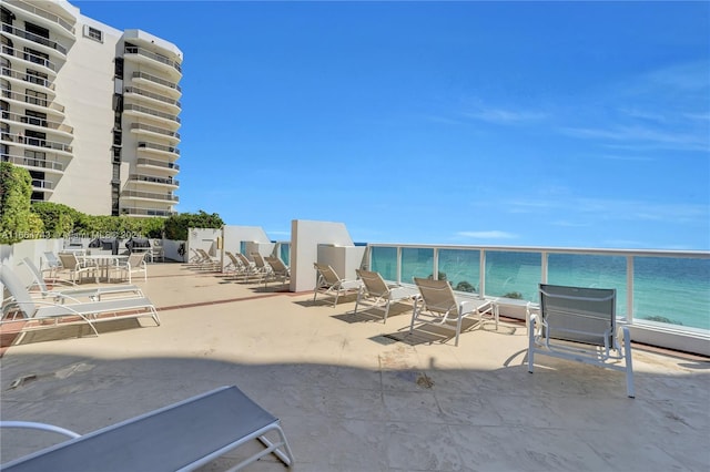 view of patio featuring a water view, a beach view, and a balcony