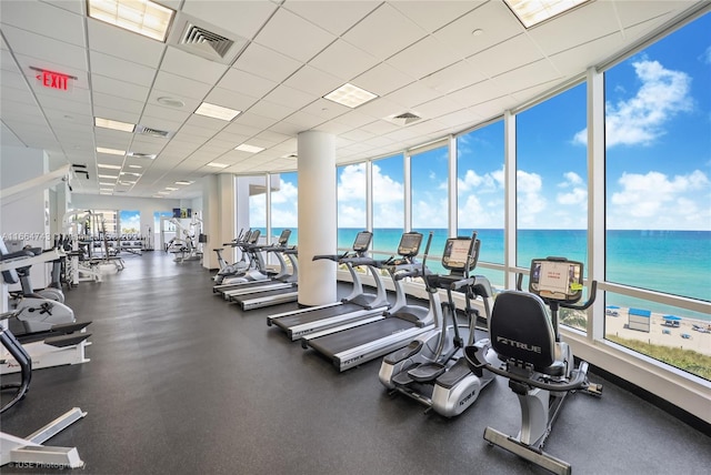 workout area with a paneled ceiling, a water view, and expansive windows