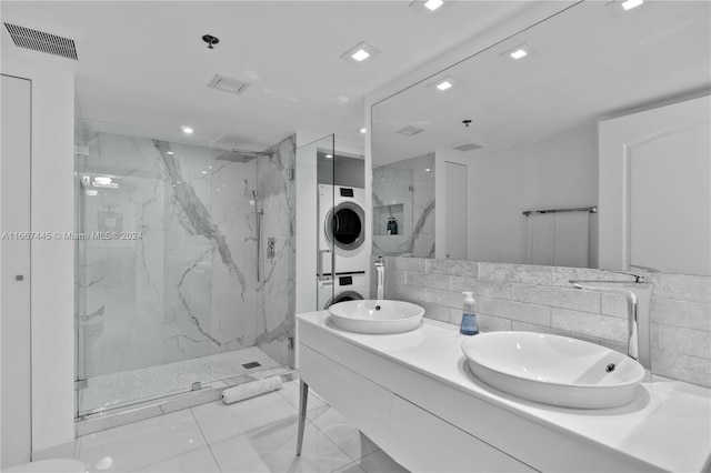 bathroom featuring tile walls, tiled shower, vanity, stacked washer / drying machine, and tile patterned flooring