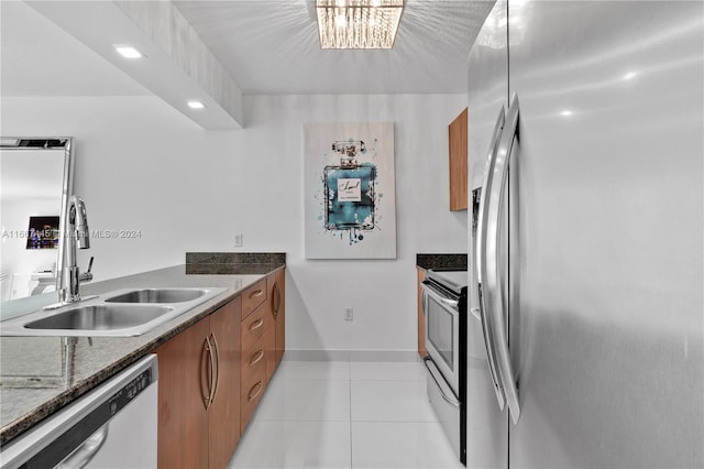 kitchen with light tile patterned floors, stainless steel appliances, sink, and dark stone counters