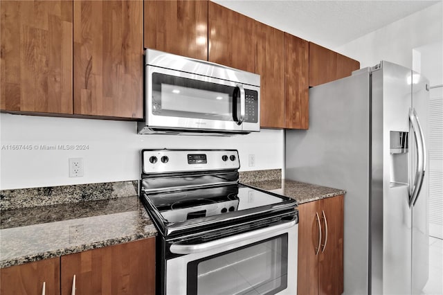 kitchen featuring a textured ceiling, dark stone countertops, and stainless steel appliances