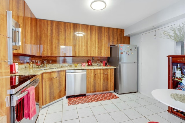 kitchen featuring light stone counters, light tile patterned floors, sink, and appliances with stainless steel finishes