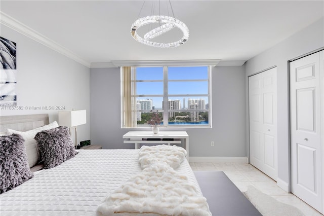 tiled bedroom featuring a chandelier, ornamental molding, and multiple closets