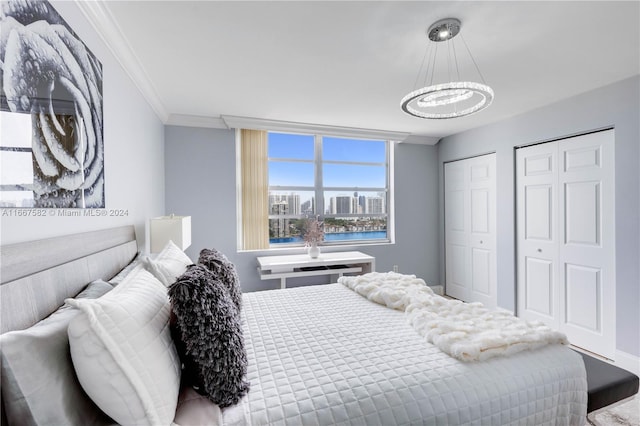 bedroom featuring multiple closets, crown molding, and a chandelier