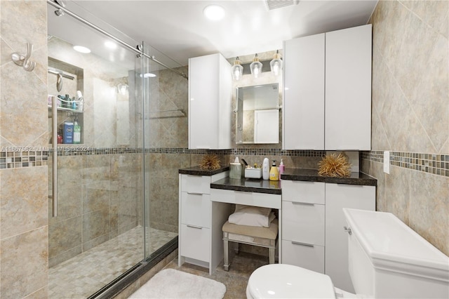 bathroom with vanity, a shower with door, and tile walls