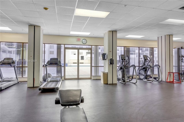 gym featuring a paneled ceiling and a healthy amount of sunlight