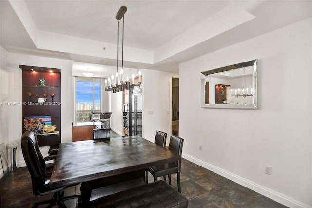 dining area featuring a raised ceiling and a chandelier