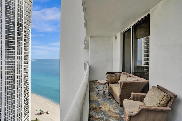 balcony with a water view and a view of the beach