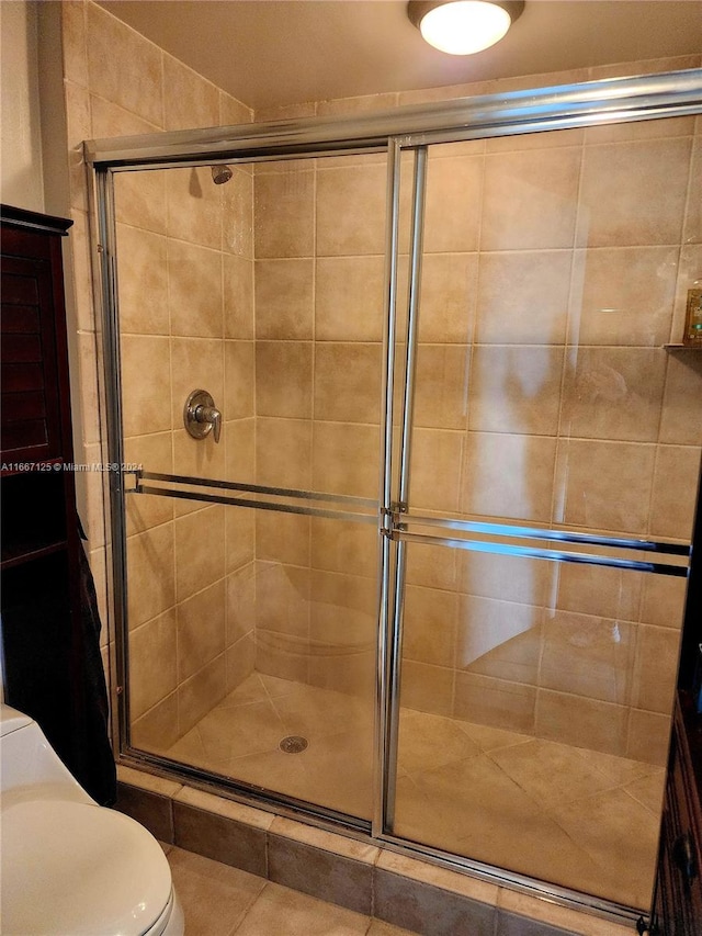 bathroom with toilet, a shower with shower door, and tile patterned flooring