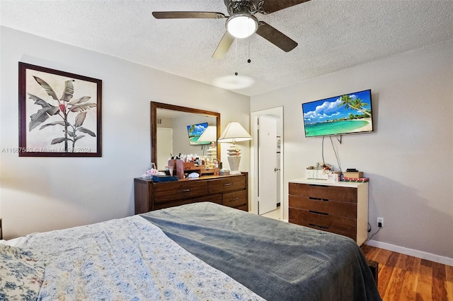 bedroom with a textured ceiling, wood-type flooring, and ceiling fan