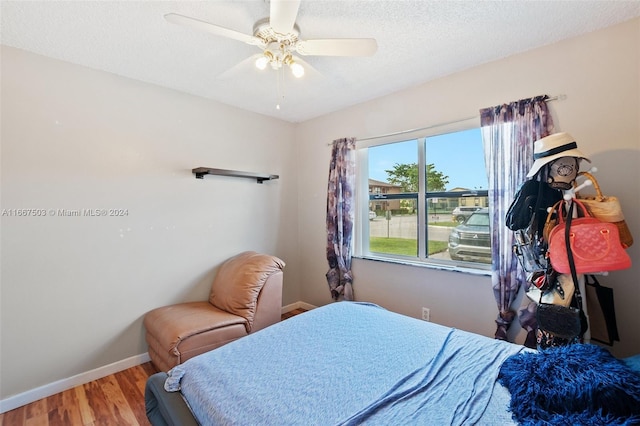 bedroom with ceiling fan, hardwood / wood-style flooring, and a textured ceiling