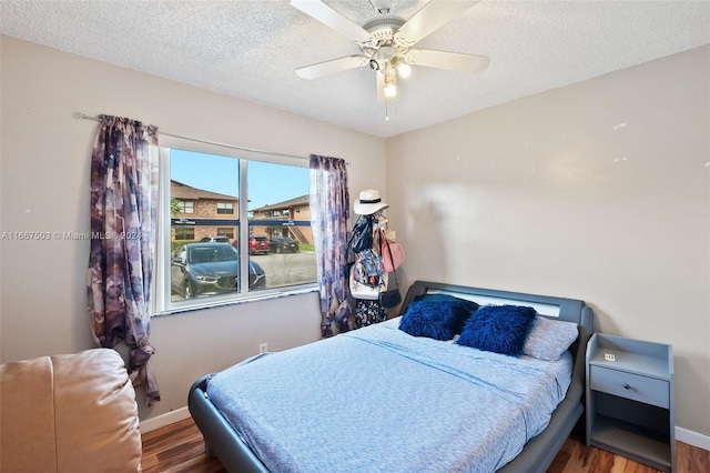 bedroom with a textured ceiling, ceiling fan, and hardwood / wood-style flooring