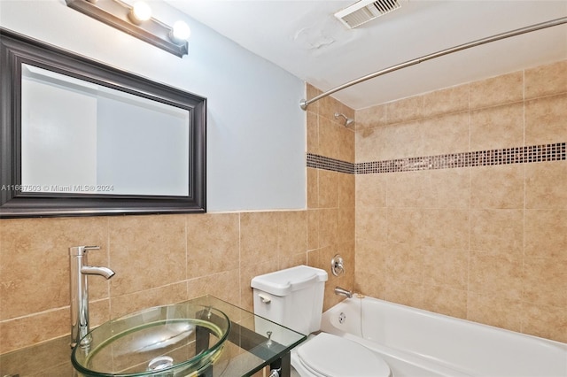 full bathroom with tiled shower / bath, vanity, tile walls, and toilet