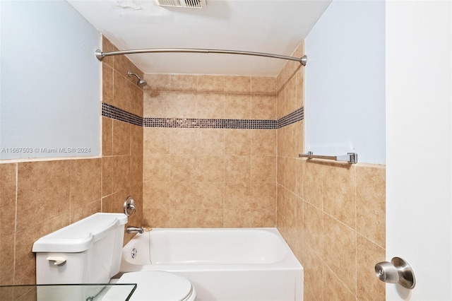 bathroom featuring tile walls, tiled shower / bath combo, and toilet