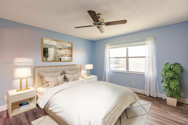 bedroom with a textured ceiling, light hardwood / wood-style floors, and ceiling fan