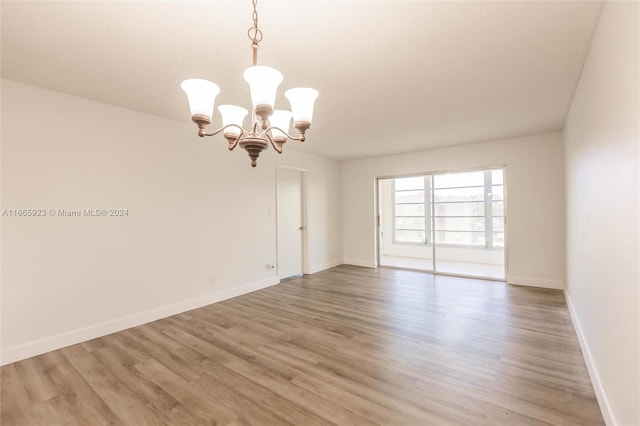 unfurnished room with hardwood / wood-style floors and a chandelier