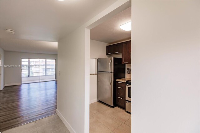 9460 Sunrise Lakes Blvd Unit 309, Sunrise, FL 33322 - kitchen with stainless steel appliances, dark brown cabinets, light tile patterned flooring, baseboards, and open floor plan