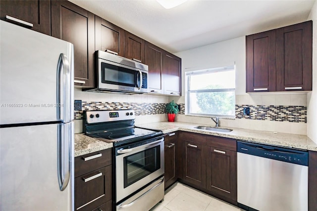 kitchen with decorative backsplash, stainless steel appliances, light stone counters, and sink