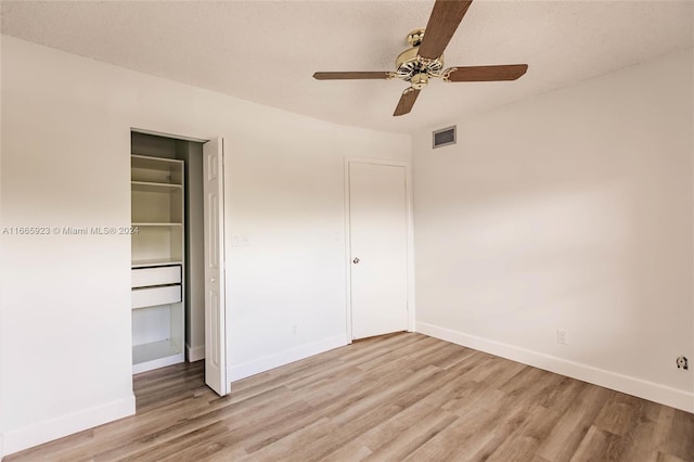 unfurnished bedroom featuring ceiling fan, a textured ceiling, light hardwood / wood-style flooring, and a closet